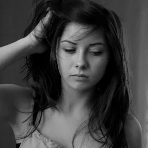 Elegant black and white portrait of a thoughtful woman in a studio setting.